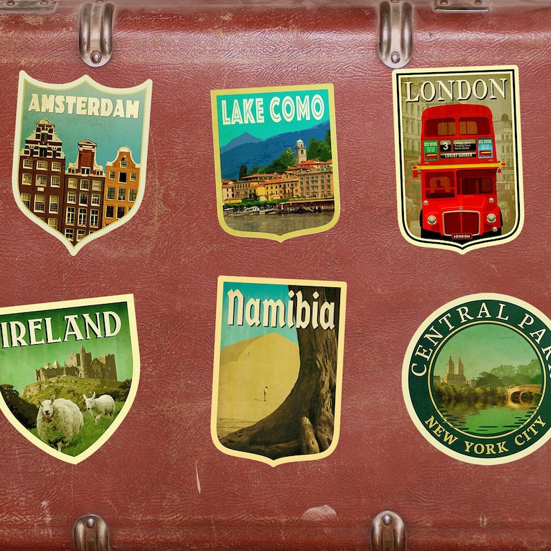 K&ouml;nnte beinhalten: Ein Vintage-Koffer mit Reiseaufklebern aus Amsterdam, Comer See, London, Irland, Namibia und Central Park, New York City.