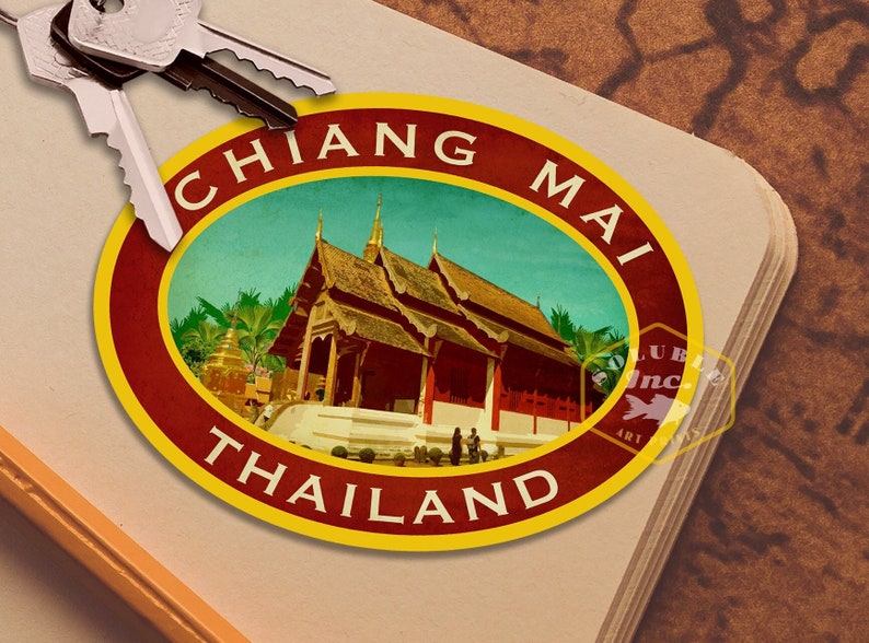 May include: A vintage-style travel sticker with a yellow, red, and brown border. The sticker features a picture of a traditional Thai temple with the text "CHIANG MAI THAILAND" in a yellow circle.