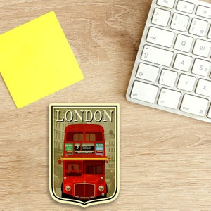 May include: A vintage-style illustration of a red double-decker bus with the word "LONDON" in a banner above it. The bus has the number "3" on the side and the words "COVENT GARDEN" on the front. The illustration is set against a background of buildings and a cloudy sky.