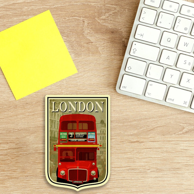 May include: A vintage-style illustration of a red double-decker bus with the word "LONDON" in a banner above it. The bus has the number "3" on the side and the words "COVENT GARDEN" on the front. The illustration is set against a background of buildings and a cloudy sky.