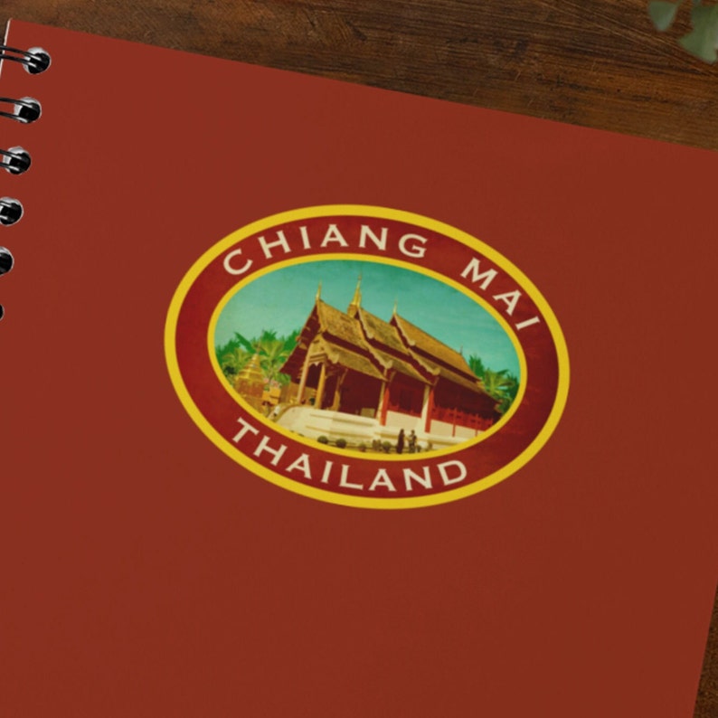 May include: A vintage-style travel sticker with a yellow border and the text "CHIANG MAI THAILAND". The sticker features a colorful image of a traditional Thai temple with a blue sky and green trees.