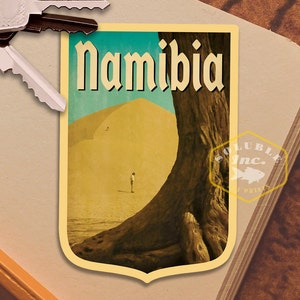 May include: A vintage travel poster featuring a large sand dune and a tree with the word "Namibia" in a bold, stylized font.