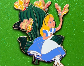 May include: Enamel pin featuring Alice in Wonderland, with blonde hair and a blue dress, reaching towards a butterfly. The pin includes a green leaf and three yellow and pink butterflies, set against a glittery green background.