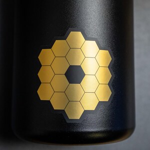 May include: A black water bottle with a gold honeycomb sticker on the side.