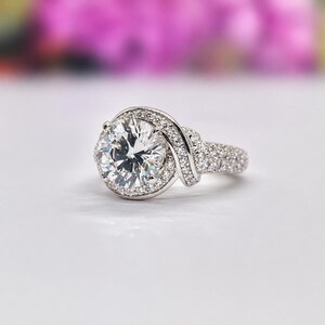 Puede incluir: Un deslumbrante anillo de compromiso con un gran diamante de talla redonda como pieza central. El anillo presenta un halo de diamantes m&aacute;s peque&ntilde;os alrededor de la piedra principal y a lo largo de la banda, creando un dise&ntilde;o elegante.