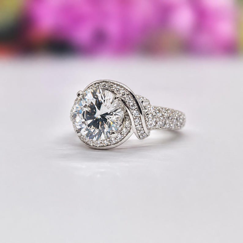 Puede incluir: Un deslumbrante anillo de compromiso con un gran diamante de talla redonda como pieza central. El anillo presenta un halo de diamantes m&aacute;s peque&ntilde;os alrededor de la piedra principal y a lo largo de la banda, creando un dise&ntilde;o elegante.