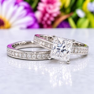 May include: A silver-toned metal ring set consisting of a band featuring a row of small round stones and a matching engagement ring with a large square princess-cut center stone and a band accented with a row of small round stones.