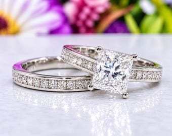 May include: A silver-toned metal ring set consisting of a band featuring a row of small round stones and a matching engagement ring with a large square princess-cut center stone and a band accented with a row of small round stones.