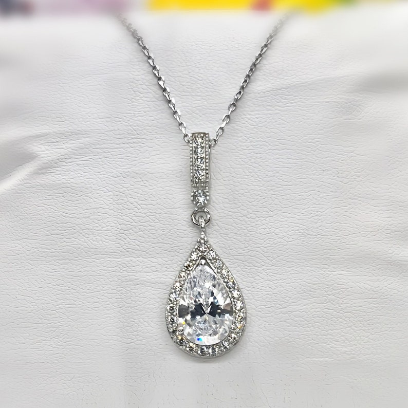 May include: A silver necklace with a pear-shaped pendant set with clear cubic zirconia stones.