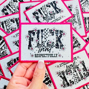 May include: A rectangular patch with a white background and a bright pink border. The design features the black text "FUCK that" with a checkered pattern on the letter U, surrounded by small pink and white flowers and the word "RESPECTFULLY".