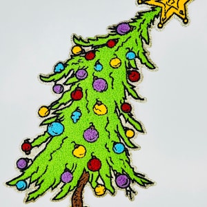 Könnte beinhalten: Ein grüner Weihnachtsbaum mit einem gelben Stern oben. Der Baum ist mit bunten Ornamenten geschmückt, darunter rot, blau, gelb und lila. Der Baum steht auf einem gelben Sockel.
