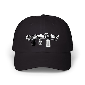 May include: A black baseball cap featuring white embroidered text that reads Classically Trained above a graphic illustration of three car pedals, including a clutch, brake, and accelerator, centered on the front of the crown.