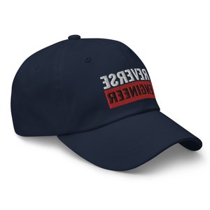 May include: A navy blue baseball cap with the text "REVERSE ENGINEER" in white and red lettering.