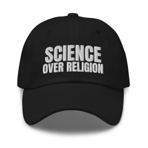 Op de afbeelding: Zwarte baseballpet met witte geborduurde tekst die "SCIENCE OVER RELIGION" luidt.