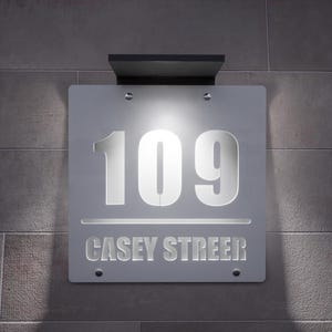 以下が含まれることがあります： モダンな照明付き住所サイン。数字「109」と通り名「CASEY STREET」が、すっきりとしたサンセリフ体で表示されています。サインは、質感のあるグレーの壁に取り付けられており、内蔵ライトが特徴です。