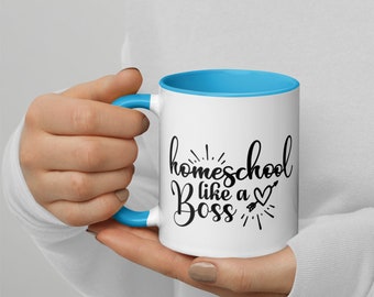 Puede incluir: Taza de cerámica blanca con borde y asa azules. La taza tiene un diseño negro que dice "homeschool like a boss" con un corazón y una flecha.