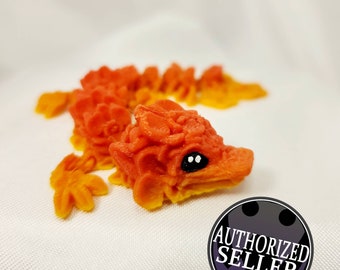 Può includere: Una statuetta di drago stampata in 3D di colore arancione e giallo con occhi neri. Il drago è arrotolato in una posizione di riposo.