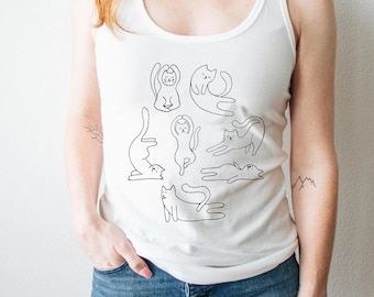 May include: White tank top with a black line drawing of cats in various yoga poses. The design includes a cat in downward dog, a cat in a seated meditation pose, and a cat in a warrior pose.