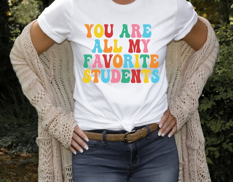 May include: White t-shirt with the text "You are all my favourite students" in colourful, retro-style lettering.