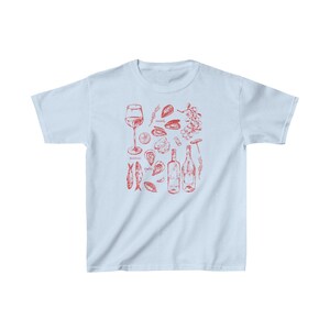 May include: Light blue t-shirt featuring a red illustration of wine, oysters, mussels, and fish. The text "oysters", "mussels", and "delicious" are included in the design.