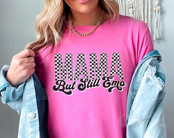 Könnte beinhalten: Pinkes T-Shirt mit einer schwarz-weißen karierten "MAMA"-Grafik und dem Text "But Still Emo" in einer Retro-Schrift.