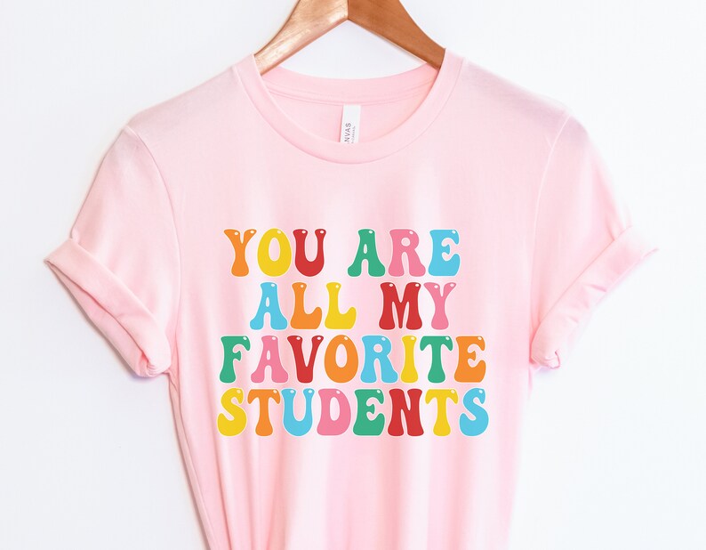 May include: Pink t-shirt with the text "You are all my favourite students" in rainbow colours.