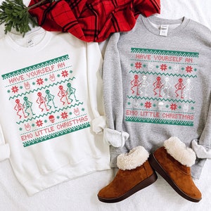 K&ouml;nnte beinhalten: Zwei wei&szlig;e und graue Sweatshirts mit einem Weihnachtsmotiv mit Skeletten und dem Text "Have Yourself an Emo Little Christmas".