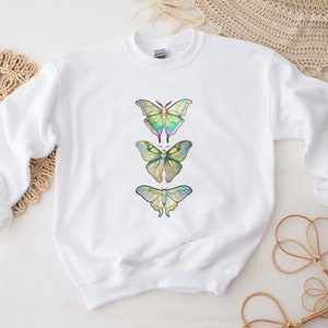 May include: White sweatshirt with a design of three iridescent butterflies in a vertical row.