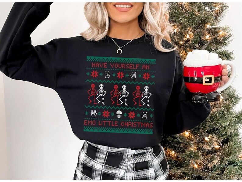 K&ouml;nnte beinhalten: Schwarzer Pullover mit einem rot-gr&uuml;nen Weihnachtsmotiv mit Skeletten mit roten K&ouml;pfen und dem Text "Have Yourself an Emo Little Christmas".