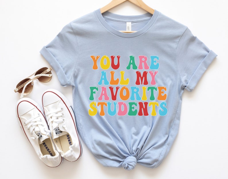 May include: Light blue t-shirt with the text "You are all my favourite students" in rainbow colours.