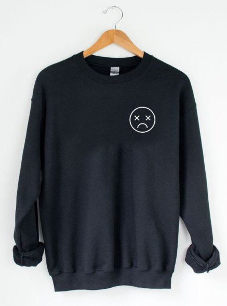 May include: Black sweatshirt with a white outline of a sad face with an X for eyes.