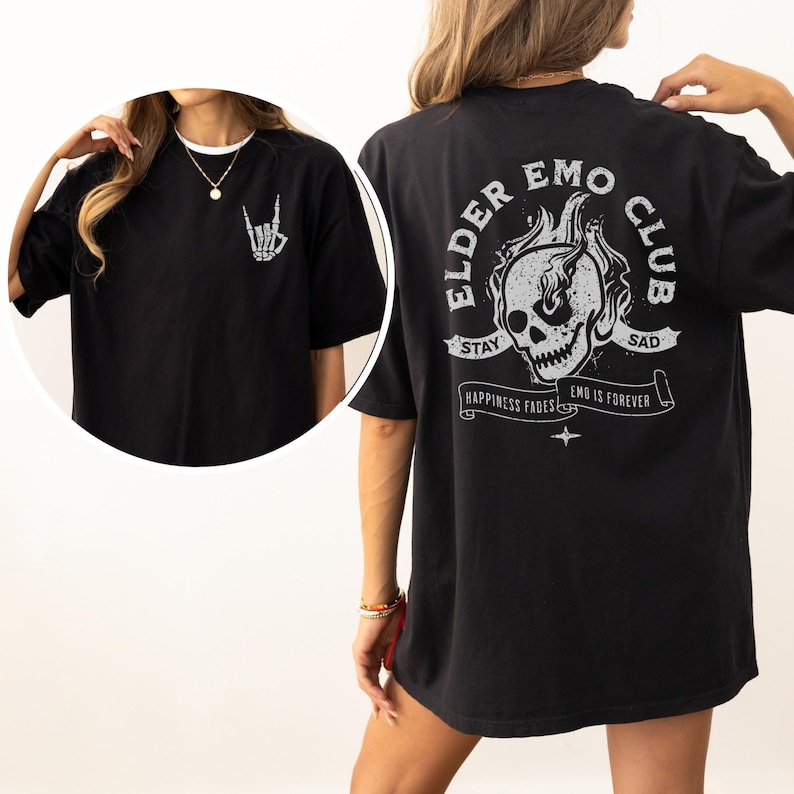 May include: Black oversized t-shirt with a graphic print of a skull in flames and the text "Elder Emo Club". The text "Stay Sad" is above the skull and "Happiness Fades Emo is Forever" is below the skull.