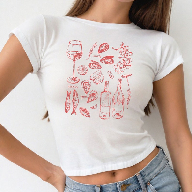 May include: White t-shirt with a red graphic design of various seafood, including oysters, mussels, sardines, and wine bottles. The text "oysters", "mussels", "sardines" is included in the design.
