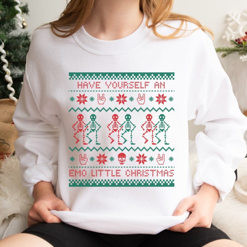 K&ouml;nnte beinhalten: Wei&szlig;er Weihnachtspullover mit einem gr&uuml;n-roten Design mit tanzenden Skeletten und dem Text "Have Yourself an Emo Little Christmas".