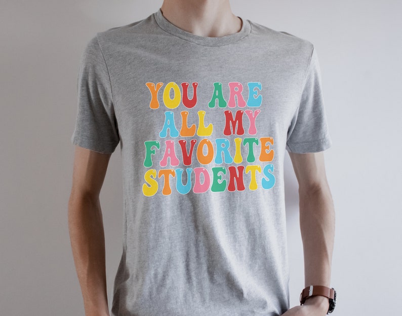 May include: A grey t-shirt with the text "You are all my favourite students" in colourful letters.