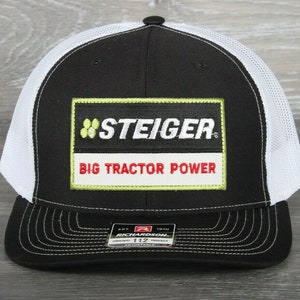 May include: Black and white trucker hat with a black patch that says "Steiger Big Tractor Power" in white and red lettering.