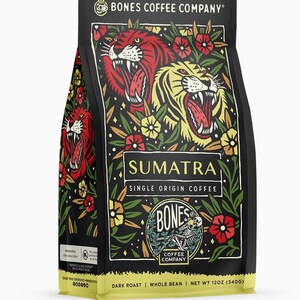 Pode incluir: Um saco de café preto com o texto "SUMATRA SINGLE ORIGIN COFFEE" e "BONES COFFEE COMPANY". O saco apresenta ilustrações de tigres e flores. O peso líquido é de 340g.