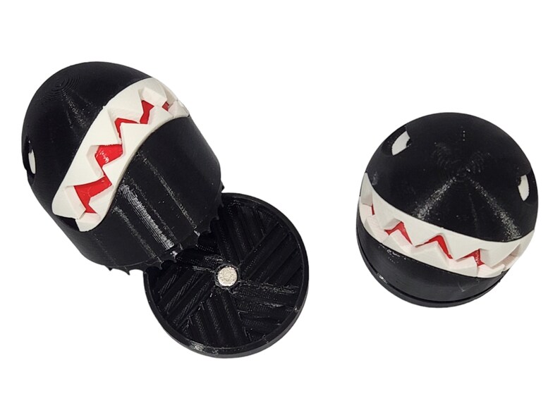 Puede incluir: Dos figuras impresas en 3D en blanco y negro de un personaje de videojuego con una sonrisa de dientes. Las figuras son de pl&aacute;stico y tienen una superficie texturizada.