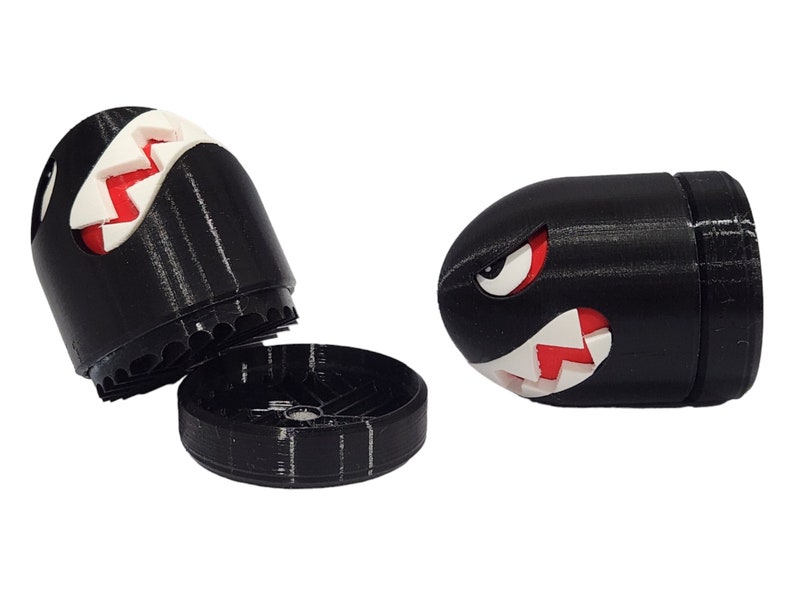 Puede incluir: Molino de 3D impreso en blanco y negro con una cara de dibujos animados roja y blanca. El molino tiene forma de bala y tiene una tapa extra&iacute;ble.