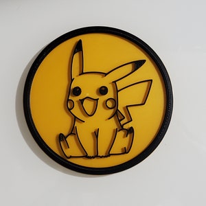 May include: A yellow and black round sticker with a cartoon image of Pikachu, a popular Pokemon character.