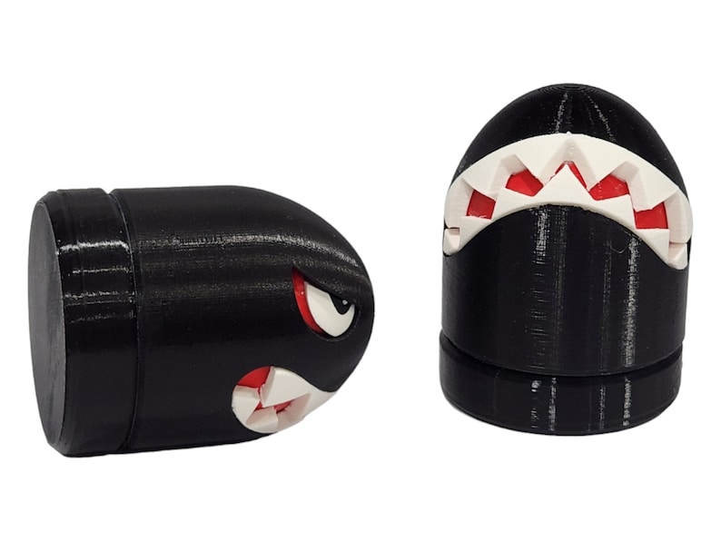 Puede incluir: Dos figuritas en forma de bala, impresas en 3D, en blanco y negro con dientes rojos. Las figuritas est&aacute;n inspiradas en un personaje de videojuego popular.