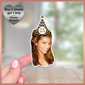 May include: A sticker featuring a woman wearing a gold and black party hat with the number 25. The sticker also includes a heart-shaped graphic with the text "Buy 2 sheets get 1 free" and "Glossy Stickers".