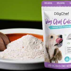 May include: A purple and white pouch of Dog Chef Calcium, a natural daily supplement for dogs. The pouch features a photo of a dog with its tongue out, and the text "Good Dog Health Comes Naturally".
