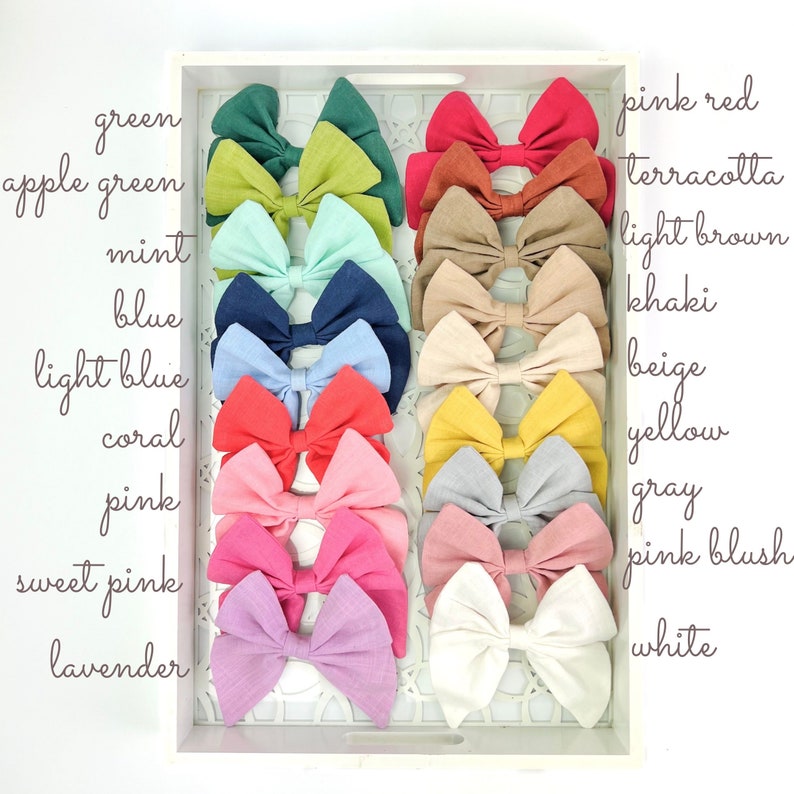 May include: A collection of 16 fabric hair bows in a variety of colors, including green, apple green, mint, blue, light blue, coral, pink, sweet pink, lavender, pink red, terracotta, light brown, khaki, beige, yellow, gray, pink blush, and white.