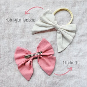 May include: Two fabric hair bows, one white and one pink. The white bow is attached to a nude nylon headband. The pink bow is attached to an alligator clip. "Nude Nylon Headband" and "Alligator Clip" are written in the image.