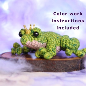 May include: A green crocheted frog wearing a gold crown sits on a wooden slice. Color work instructions are included.