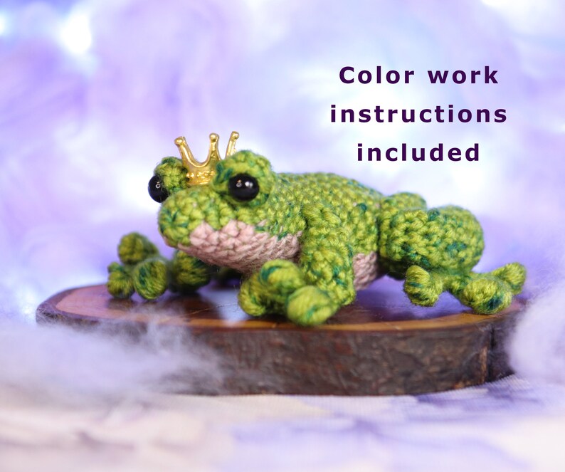 May include: A green crocheted frog wearing a gold crown sits on a wooden slice. Color work instructions are included.