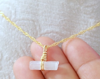 May include: A gold chain necklace with a white selenite crystal pendant wrapped in gold wire.