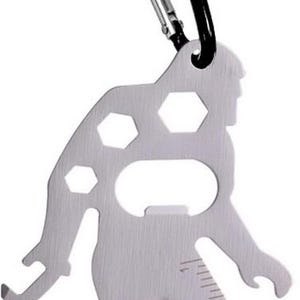 May include: A silver multi-tool in the shape of Bigfoot, with a black carabiner clip. The tool includes a bottle opener, hex wrenches, and a ruler marked in inches. The Bigfoot design has a cutout for the bottle opener.