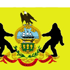 May include: A yellow flag in the shape of Pennsylvania, featuring a state seal with a ship, eagle, and the words "Virtue, Liberty, and Bigfoot." Two black Bigfoot figures flank the seal.
